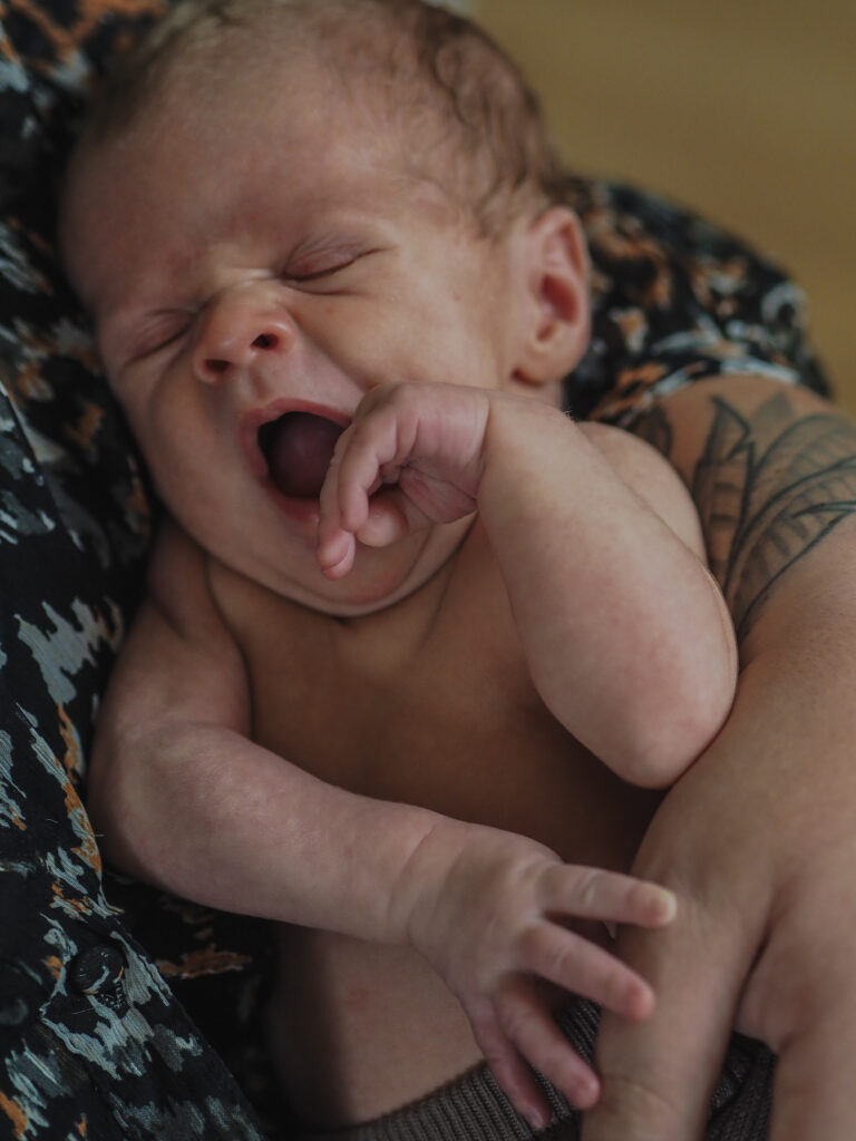 Familienfotografie Herten - gähnendes Neugeborenes auf Mamas Arm