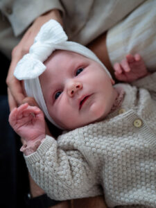 Familienfotografie Herten - Neugeborenes mit Schleife auf dem Kopf