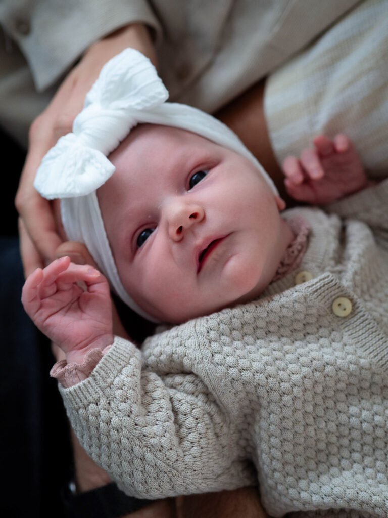 Familienfotografie Herten - Neugeborenes mit Schleife auf dem Kopf