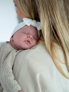 Neugeborenes schlafend auf der Schulter der Mutter