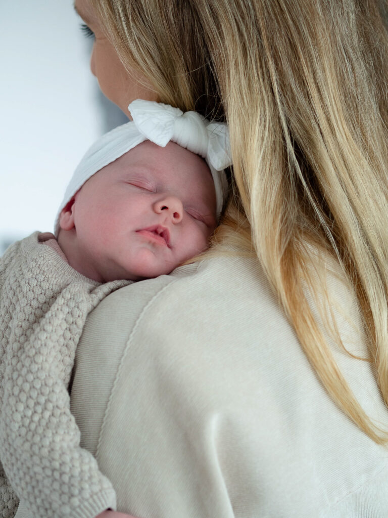 Neugeborenes schlafend auf der Schulter der Mutter