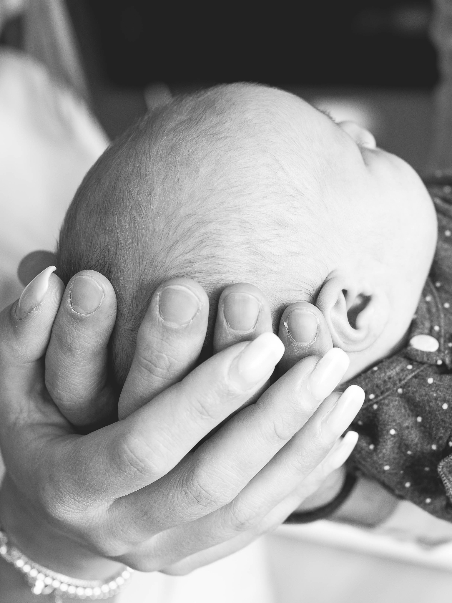 Familienfotografie Herten - Kopf eines Neugeborenen in den Händen der Eltern