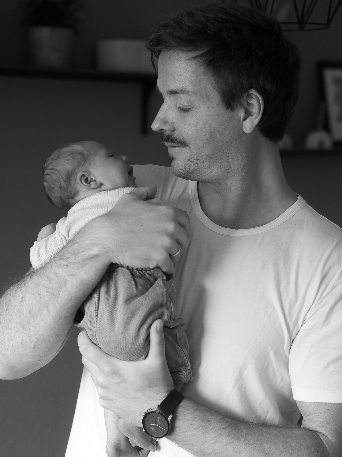 Vater hält seine neugeborene Tochter im Arm - Homestory im Wohnzimmer