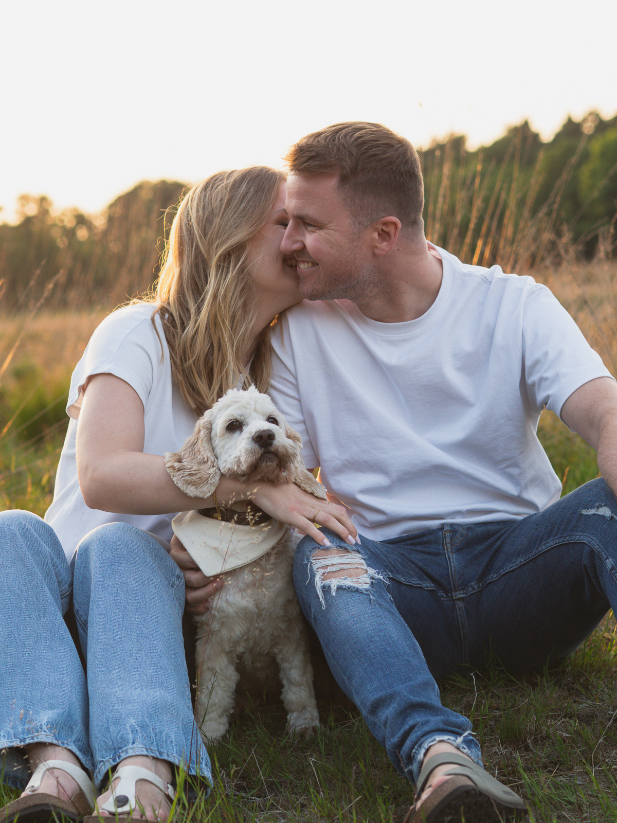 verliebtes Pärchen im Sitzen kuschelnd mit deren Hund