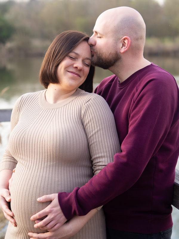 Schwangere lehnt sich liebevoll an ihrem Mann an