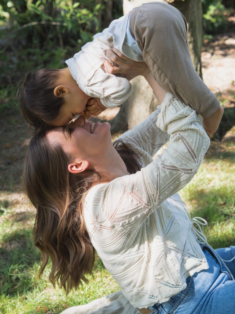 Mama hebt ihren Sohn hoch und beide kuscheln Stirn an Stirn