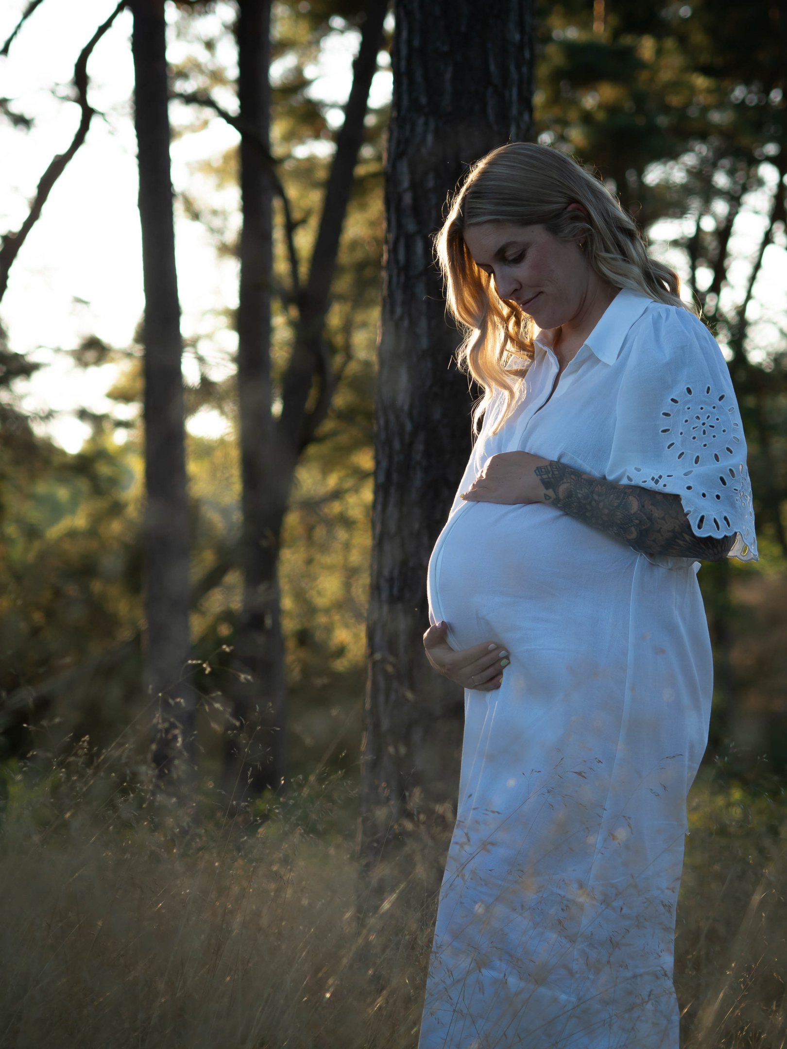 Schwangere im Wald beim Sonnenuntergang