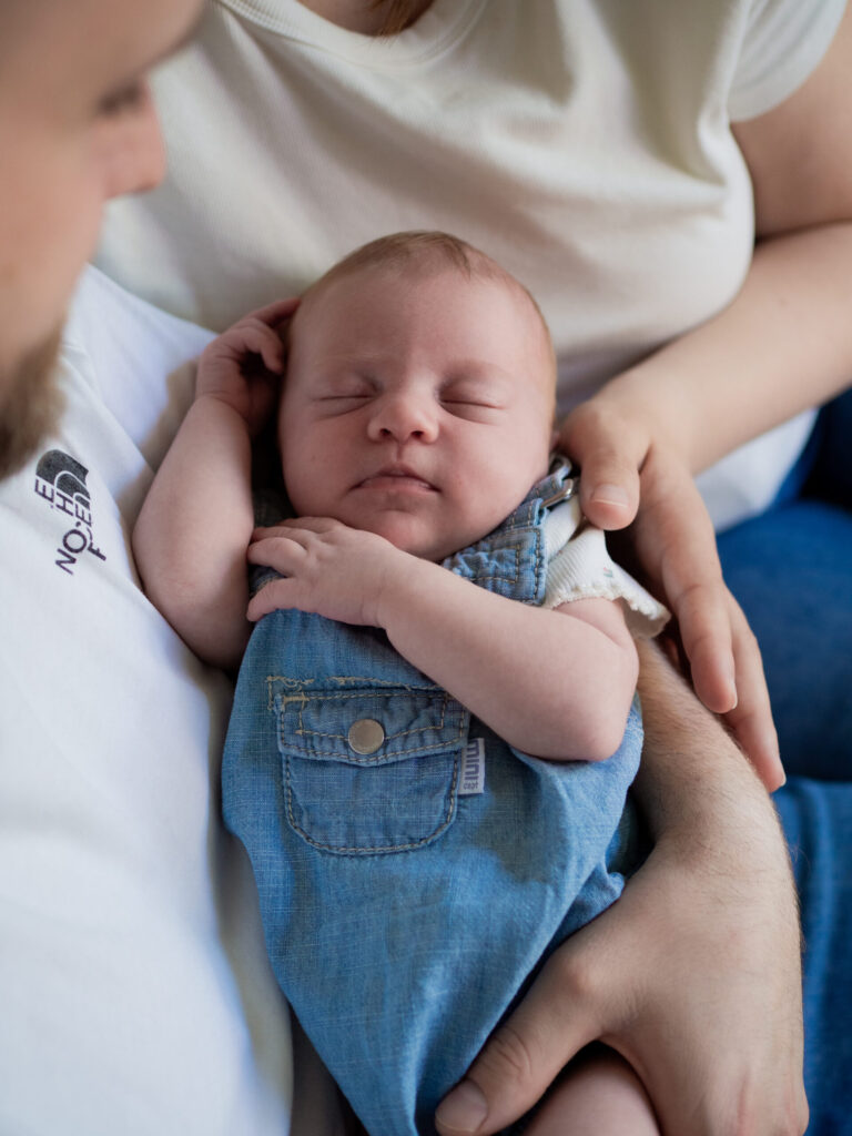 Baby eingekuschelt bei Mama und Papa im Arm