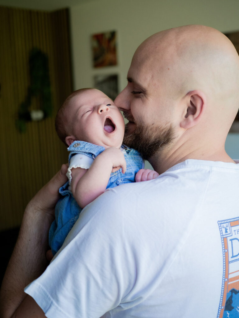 gähnendes Baby angelehnt an Papas Schulter